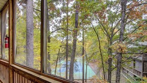 A wooden deck with a view of a forest and a tennis court.