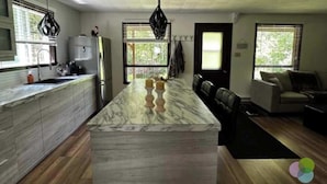 Een moderne keuken met een marmeren eiland, een inbouwoven en een groot raam.