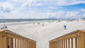 A beach with a wooden walkway leading to the shore, sandy beach, and ocean.