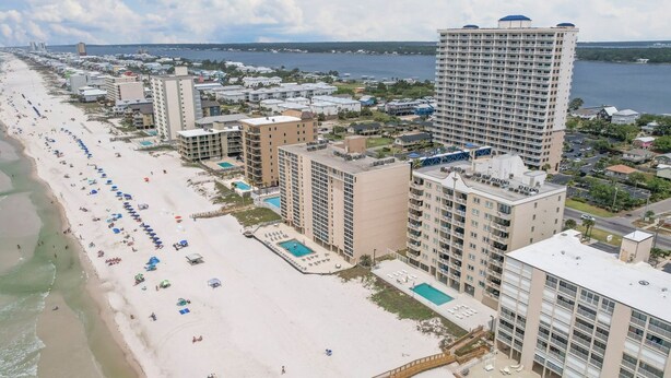 A beachfront hotel with multiple buildings, a sandy beach, and a swimming pool.