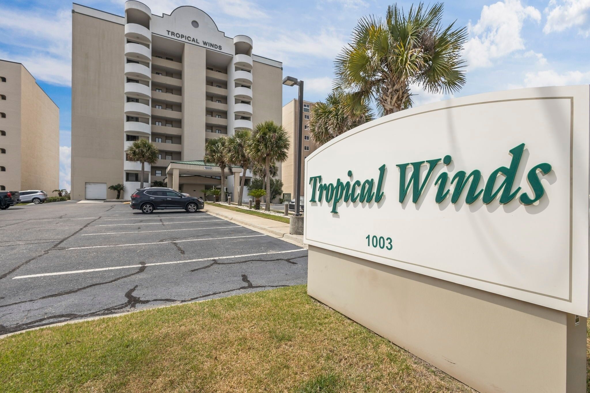 Schild für das Hotel Tropical Winds mit Parkplatz davor.
