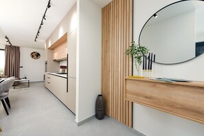 A modern kitchen with wooden cabinets, a round mirror, and a potted plant. - Villa Evita Zadarvillas (Škabrnja)