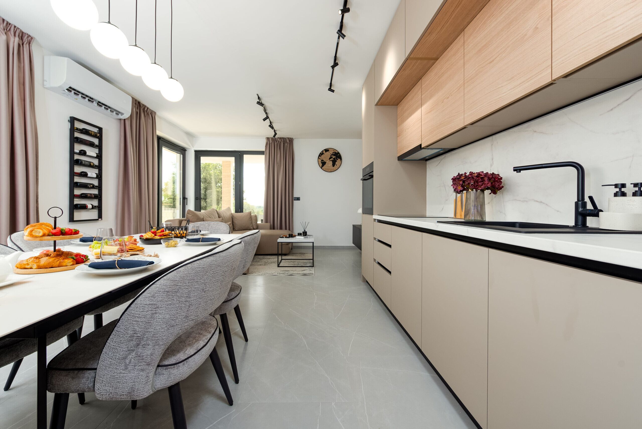 Een moderne keuken met een eethoek, voorzien van een wijnrek, een groot raam en een minimalistisch ontwerp.