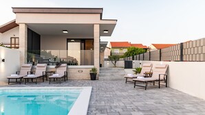 A modern outdoor pool area with lounge chairs and a clear view of the pool. - Villa Evita Zadarvillas (Škabrnja)