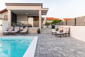Ein moderner Poolbereich im Freien mit Liegestühlen und freiem Blick auf den Pool.