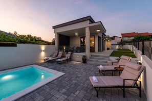 A modern outdoor pool area with lounge chairs and a covered seating area. - Villa Evita Zadarvillas (Škabrnja)