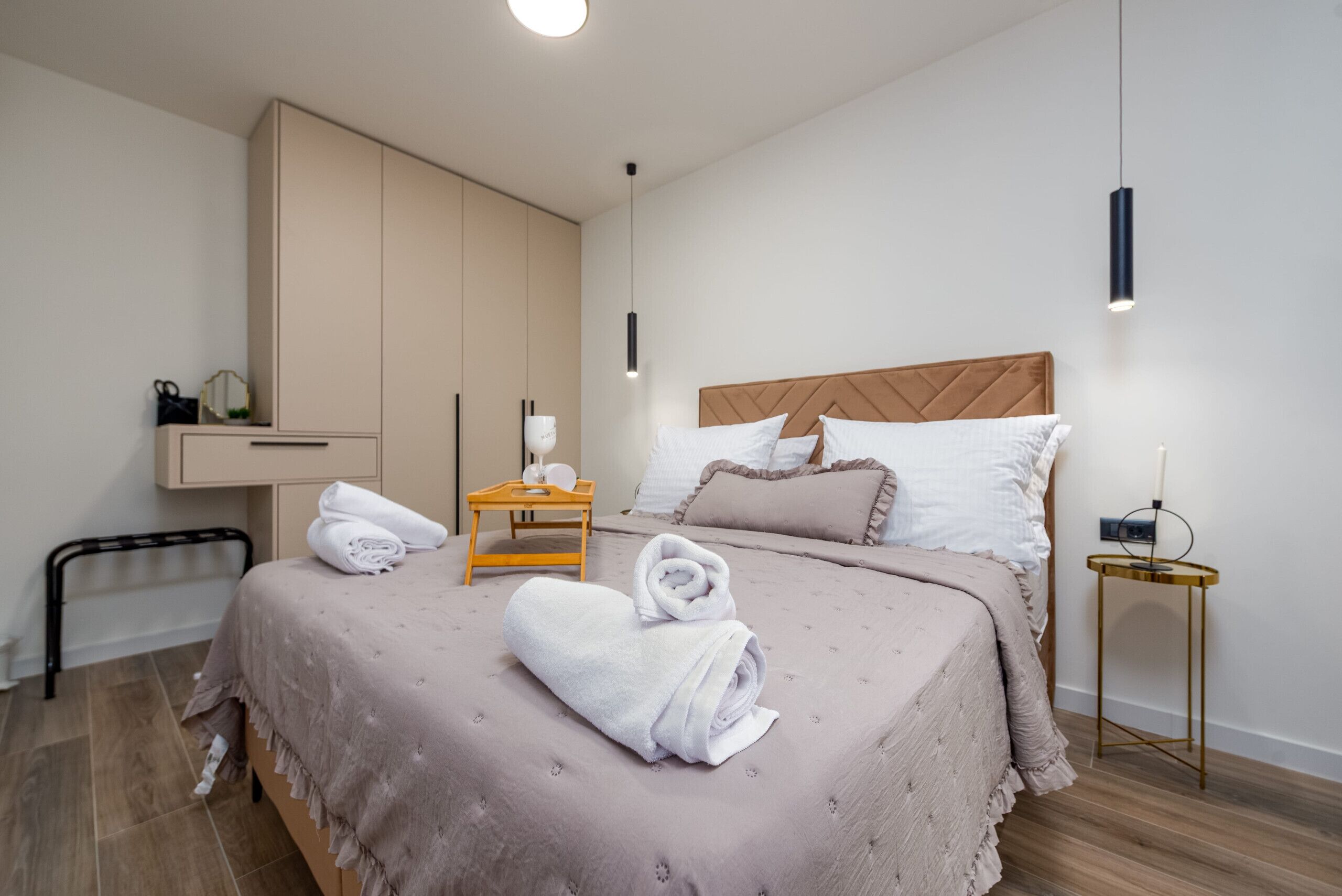 Une chambre moderne avec un grand lit, une table de chevet, une armoire et un luminaire suspendu.
