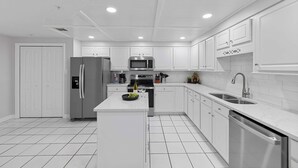 Une cuisine moderne avec des meubles blancs, des appareils en acier inoxydable et un îlot central.