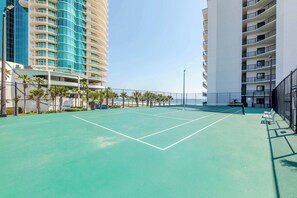 A tennis court with a net, surrounded by a fence, and adjacent to high-rise buildings. - The Palms 514- Beachfront condo, 2 bedroom 2 bathroom , 5th floor (Orange Beach)