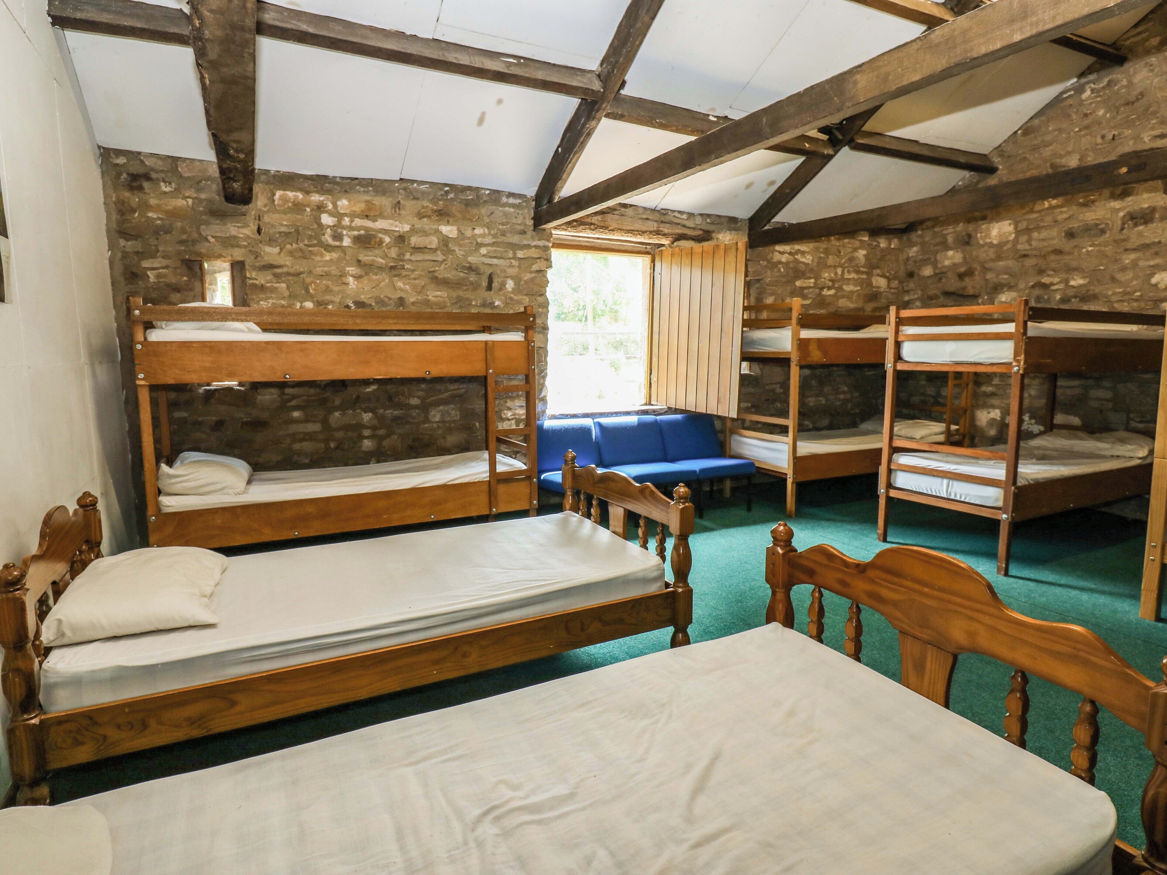 A rustic room with bunk beds, a wooden table, and stone walls.