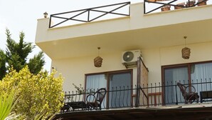 A two-story building with a stone facade, a balcony with a wrought iron railing, and a small garden area with a palm tree. - Loca Hill (Marmaris)