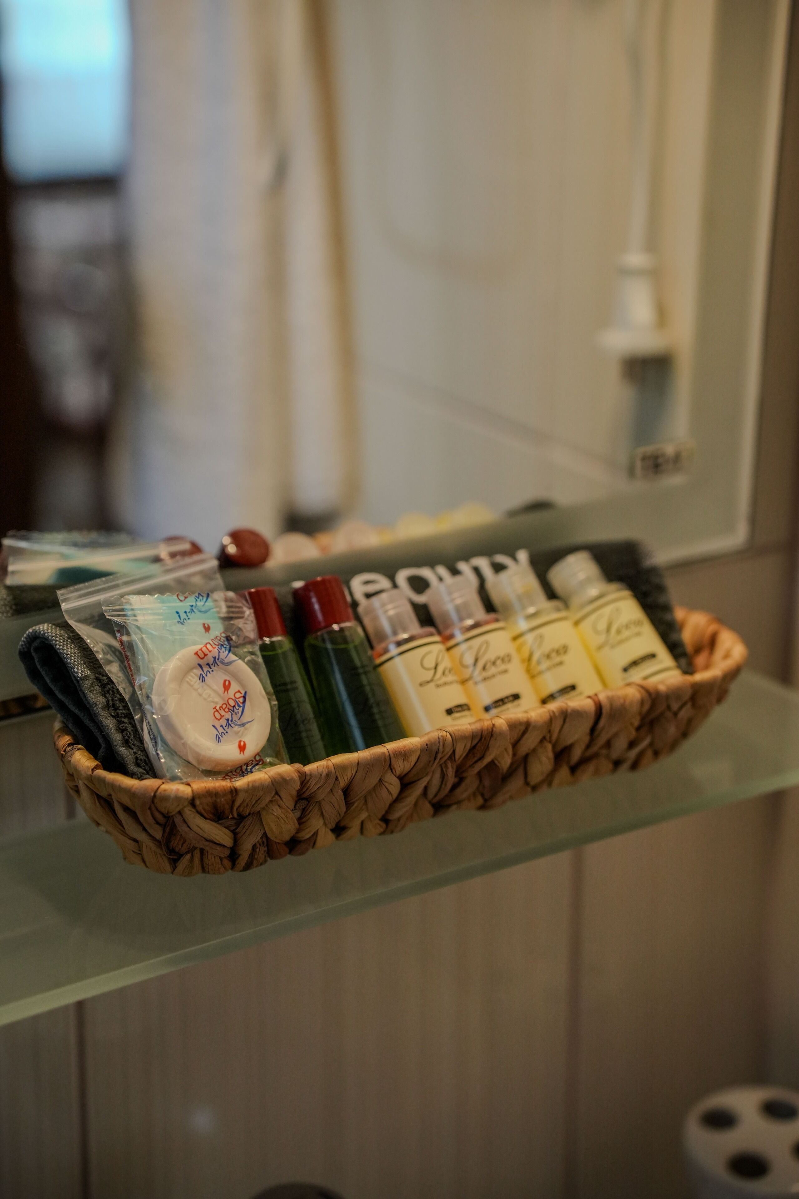A wicker basket containing toiletries on a glass shelf.