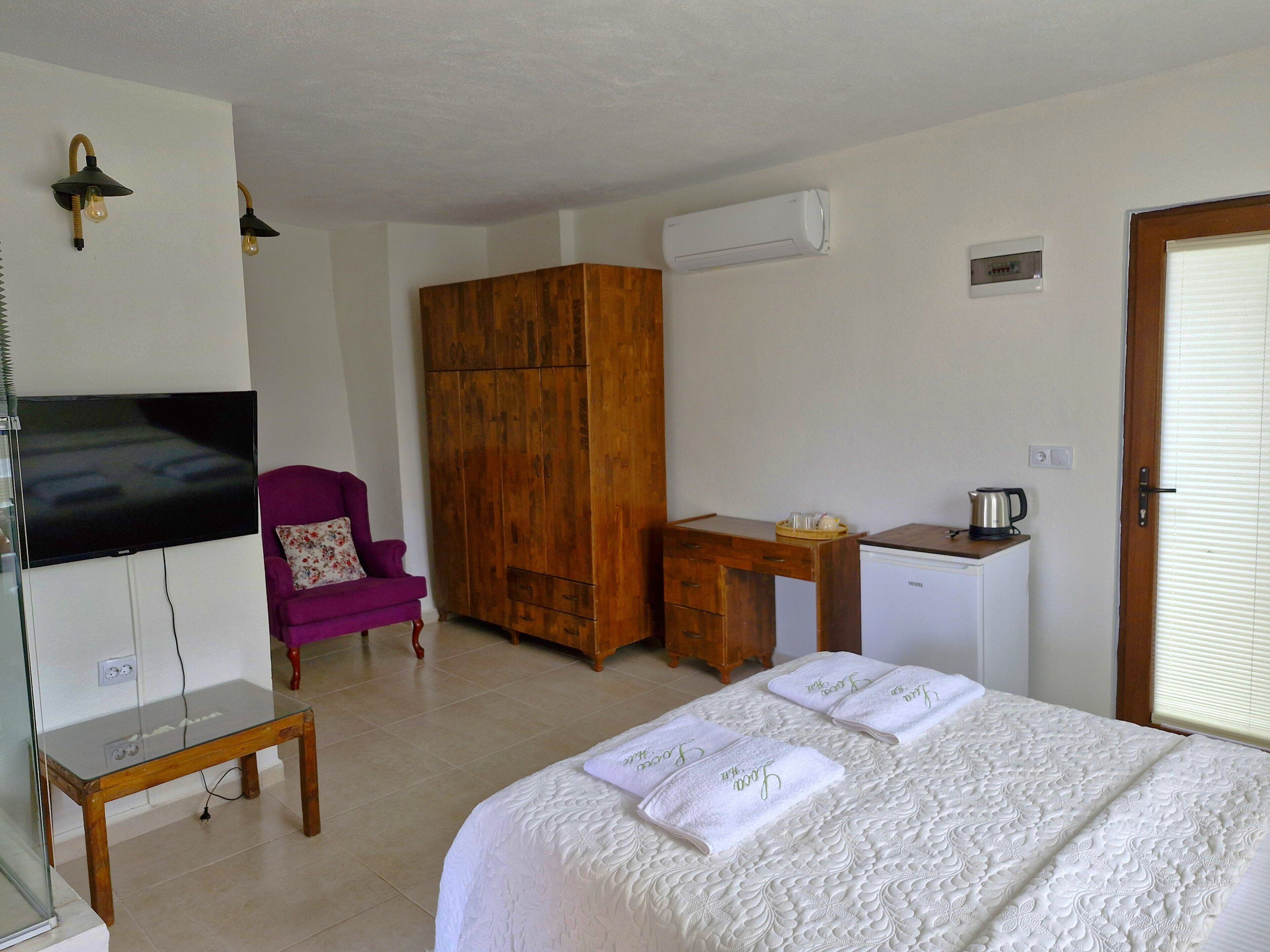 Habitación de hotel con cama, escritorio, silla, televisor, aire acondicionado y armario.