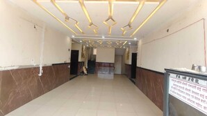 A hotel corridor with a tiled floor, a reception desk, and a staircase leading to another floor. - Agrawal Bhawan (Ujjain)