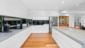 Une cuisine moderne avec des meubles blancs, un plan de travail en marbre et un plancher en bois.