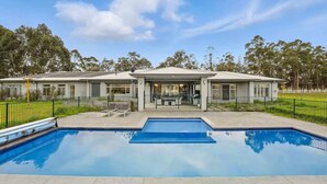 Une maison à deux étages avec une piscine à l’avant.