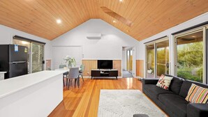 A modern kitchen with a white countertop, a black refrigerator, and a dining area with a table and chairs.