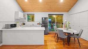 A modern kitchen with white cabinetry, a central island, and a dining area with grey chairs.