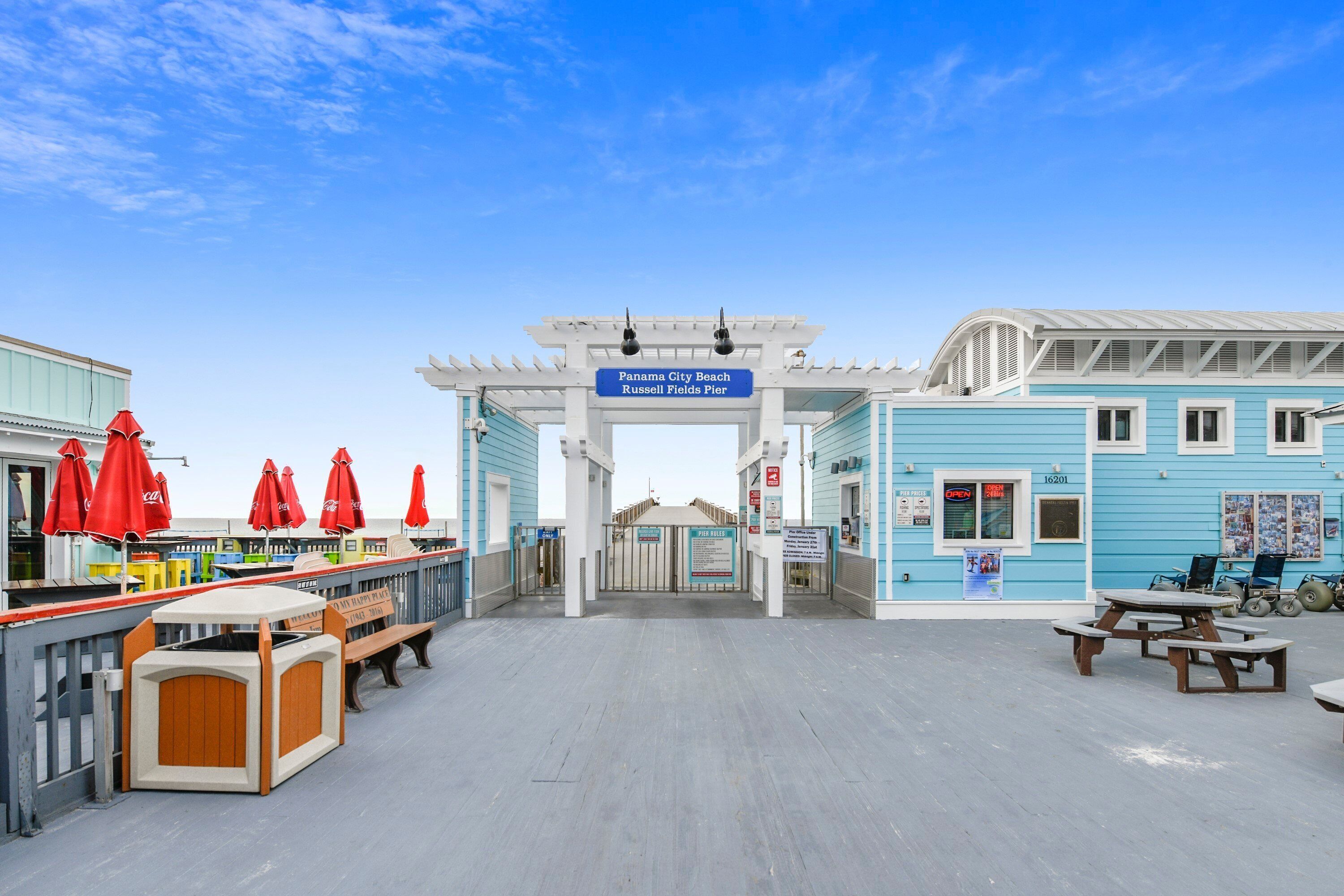 A beachside pier with a sign reading "Panama City Beach Russell Fields Pier."