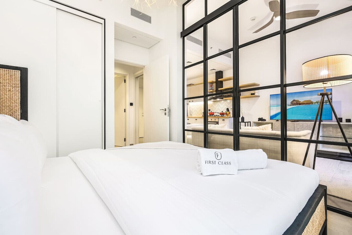 Ein Hotelzimmer mit Bett, einer Glastrennwand, Blick auf die Küche und einem Fernseher.