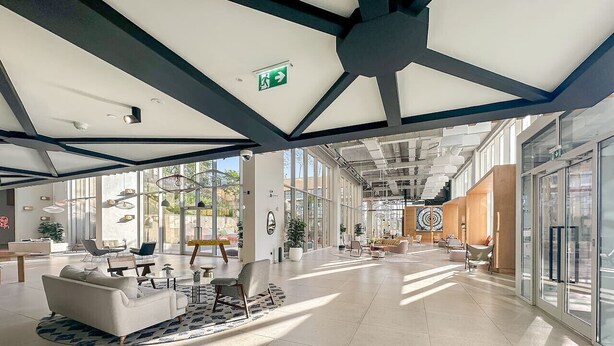 Un hall d’entrée spacieux, doté d’un plafond haut, de meubles modernes et de grandes fenêtres qui laissent entrer la lumière naturelle.