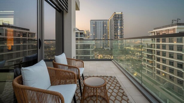 A balcony with wicker furniture, a glass railing, and a city view.
