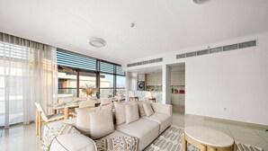 A modern living room with a sofa, dining table, and kitchen area.