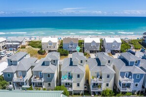 A beachfront residential area with multiple two-story houses featuring balconies and a view of the ocean.