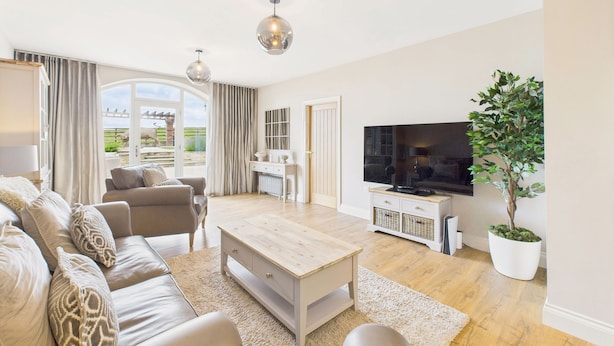 A modern living room with a sofa set, a coffee table, a TV, and a potted plant. - Host Stay Glenridge House Retreat (Wooler)