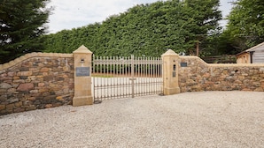 A gated entrance with a stone wall and a gravel driveway leading to a building labeled "Glenridge House." - Host Stay Glenridge House Retreat (Wooler)