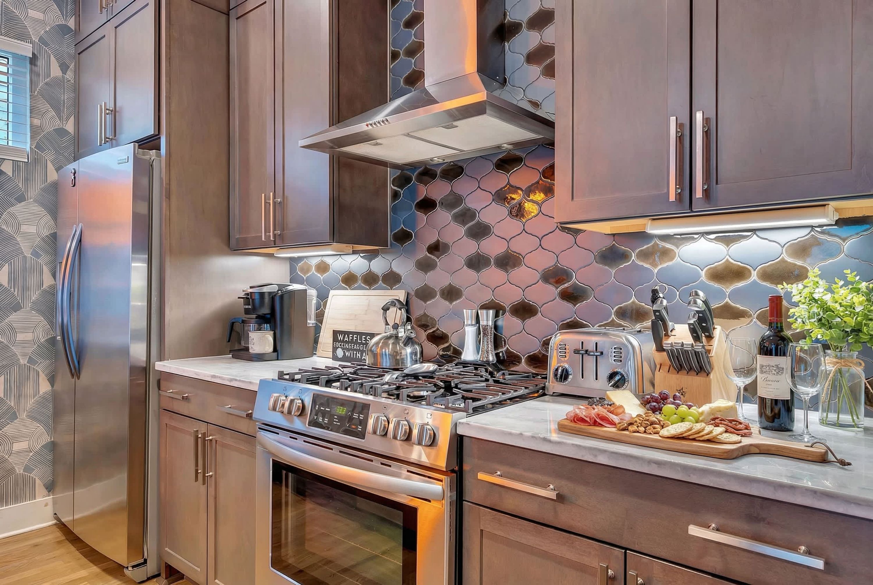A modern kitchen with stainless steel appliances, wooden cabinets, and a patterned backsplash.