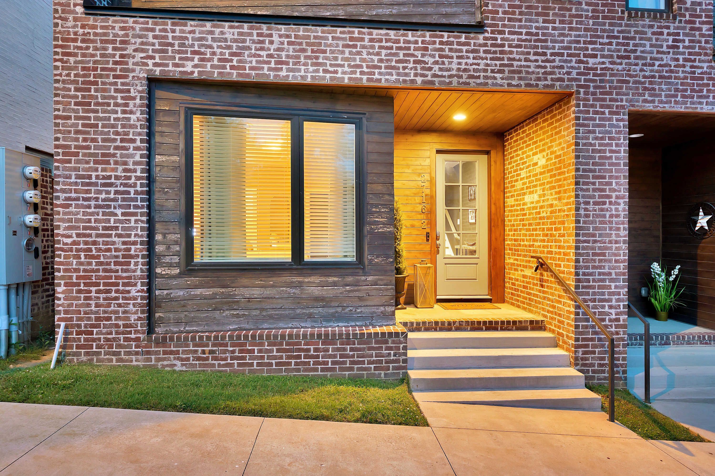A modern house with a brick exterior, a front door, and a set of steps leading to the entrance.