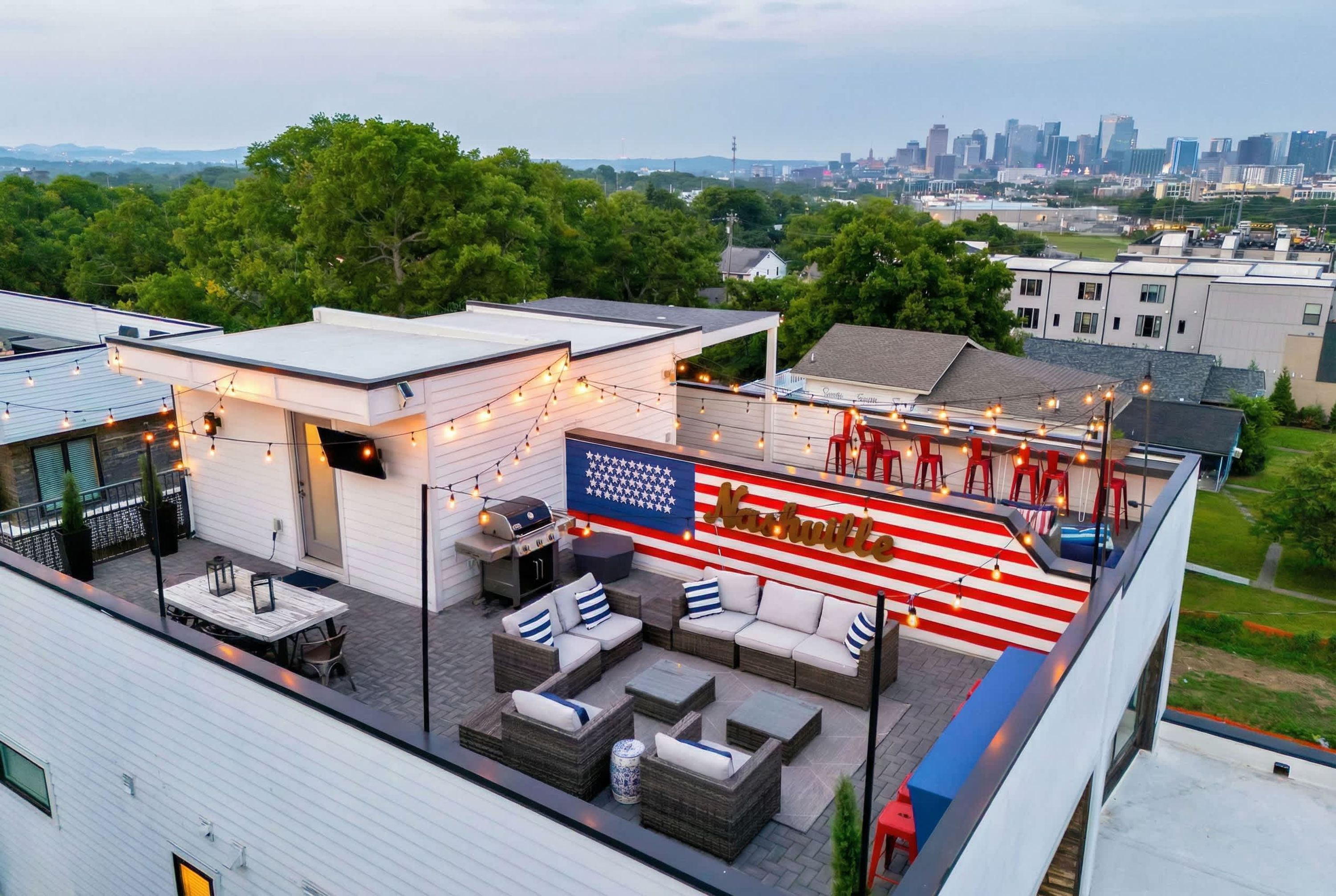 A rooftop patio with outdoor seating, a barbecue grill, and a large American flag.