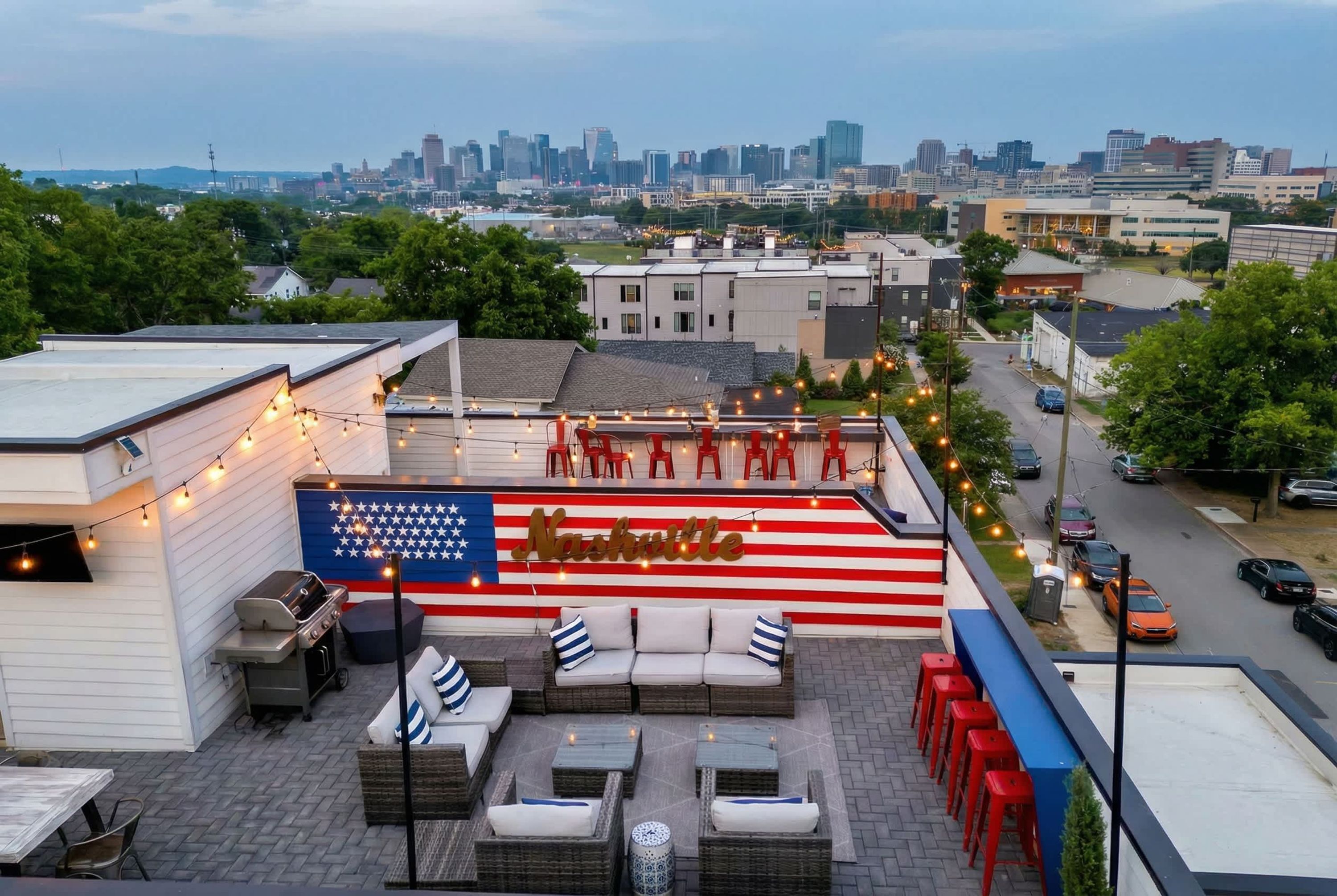 A rooftop patio with outdoor seating, a grill, and a large American flag backdrop.
