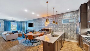 A modern kitchen with a central island, wooden flooring, and stainless steel appliances. - Rooftop Deck Shuffleboard BBQ Near Downtown (Nashville)