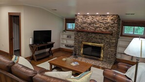 A living room with a stone fireplace, leather sofas, a coffee table, and a television.