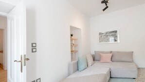 Et moderne, minimalistisk værelse med en sofa, en lille reol og et indrammet kunstværk på væggen.
