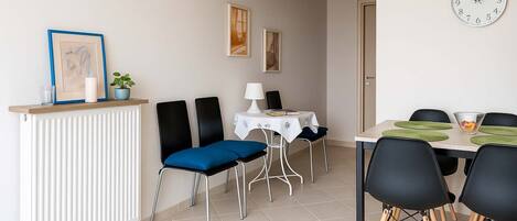 Un comedor con una mesa, sillas, un reloj y cuadros en la pared.