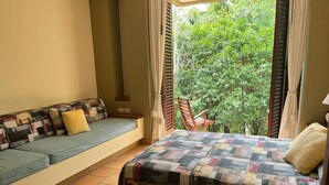 Una stanza con un letto, una poltrona e vista su spazi verdi.