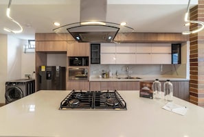 Una cocina moderna con una isla central, electrodomésticos de acero inoxidable y una pared decorada con ladrillos.