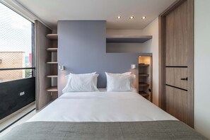 Un dormitorio moderno con una cama grande, estanterías empotradas y un armario.