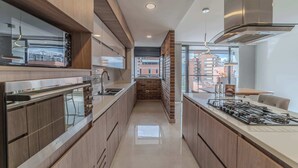 A modern kitchen with a central island, stainless steel appliances, and a view of the city through large windows. - w Elegant 3BR w Outdoor Balcony (Medellín)