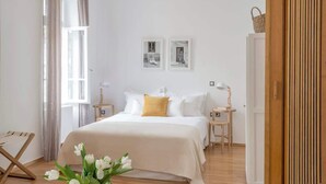 A bedroom with a bed, two bedside tables, a nightstand, a wooden chair, a window with curtains, and two framed pictures on the wall. - Athens Residence Cozy Suite Near Acropolis (Athens)