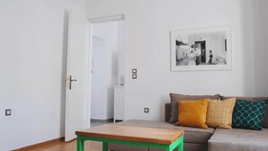 A living room with a sofa, a coffee table, and a door leading to another room. - Athens Residence Cozy Suite Near Acropolis (Athens)
