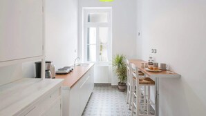 A modern kitchen with white cabinets, a wooden countertop, a sink, and a green pendant light. - Athens Residence Cozy Suite Near Acropolis (Athens)