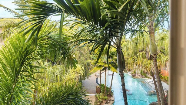 A pool area with palm trees, a clear blue sky, and a stone pathway leading to the pool. - Family Friendly 2BR Apartment with Resort Pool (Westcourt)