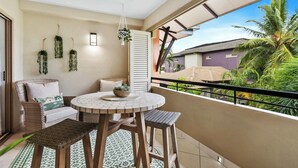 A balcony with wicker furniture, a ceiling fan, and hanging plants. - Family Friendly 2BR Apartment with Resort Pool (Westcourt)