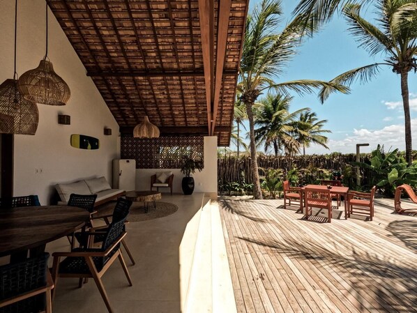 A covered outdoor area with wooden furniture, a dining table, and chairs.