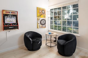 A room with two black chairs, a small round table, and a window with a view of trees. - 5 Bedroom Home With Firepit (San Diego)