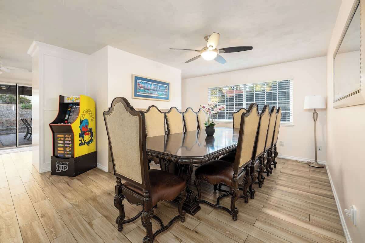 A dining room with a long table, ornate chairs, a ceiling fan, and a jukebox.